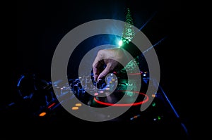 Dj mixer with headphones on dark nightclub background with Christmas tree New Year Eve. Close up view of New Year elements or symb