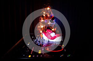 Dj mixer with headphones on dark nightclub background with Christmas tree New Year Eve. Close up view of New Year elements or symb