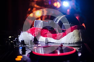 Dj mixer with headphones on dark nightclub background with Christmas tree New Year Eve. Close up view of New Year elements or symb