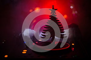 Dj mixer with headphones on dark nightclub background with Christmas tree New Year Eve. Close up view of New Year elements or symb