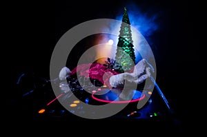 Dj mixer with headphones on dark nightclub background with Christmas tree New Year Eve. Close up view of New Year elements or symb