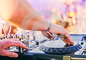 Dj mixing at beach party festival with people dancing in the background - Deejay playing music mixer audio outdoor