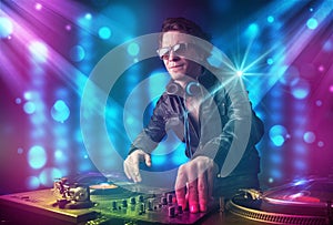 Dj mixing music in a club with blue and purple lights