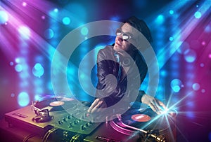 Dj mixing music in a club with blue and purple lights