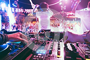 Dj mixing outdoor at beach party festival outdoor with crowd of people in background - Soft focus on left hand - Fun, summer,