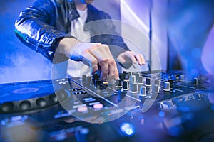 Dj mixing at party festival with blue lights and smoke in background