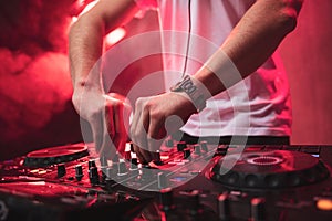 Dj mixing at party festival with red light and smoke in background photo