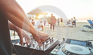 Dj mixing at sunset beach party in summer vacation outdoor - Disc jockey hands playing music for tourist people in chiringuito