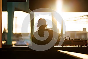 DJ performing with headphones at sunset