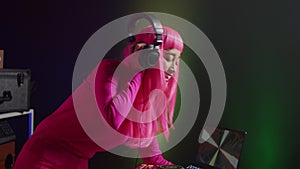 Dj with pink hair playing eletronic song at professional mixer