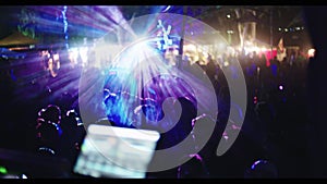 DJ playing in a large trance party with large crowd of people dancing