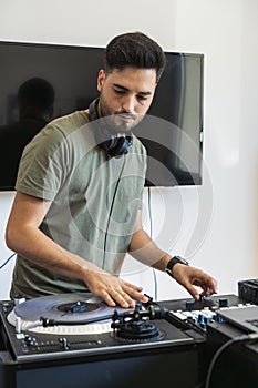 DJ playing the turntable while music plays in his studio