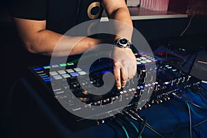 DJ plays hands on professional mixer at night club