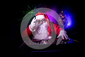 Dj Santa Claus at Christmas with glasses and snow mix on New Year`s Eve event in the rays of light