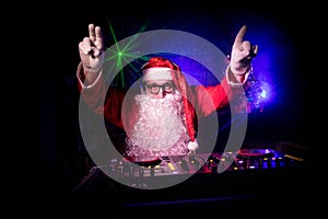 Dj Santa Claus at Christmas with glasses and snow mix on New Year`s Eve event in the rays of light