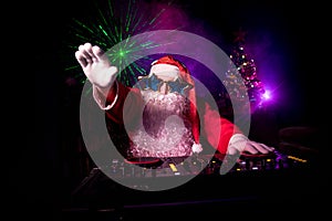 Dj Santa Claus at Christmas with glasses and snow mix on New Year`s Eve event in the rays of light