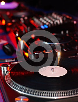 Dj turntables needle cartridge on black vinyl record with music. Close up, focus on turntable and audio disc record