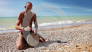 Djembe traditional Drum Player beat rythm on the lonely beach