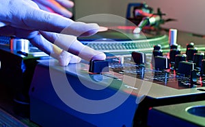 DJs hand tweaks the cross fader of a music mixer