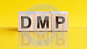 DMP - Data Management Platform - word is made of wooden building blocks lying on the yellow table