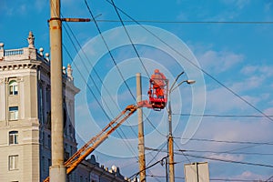 Electrician repairing wire of the power line with bucket hydraulic lifting platform on blue sky