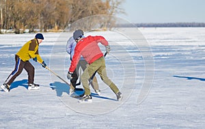 Three mature man fighting for the pack while playing amateur hockey on a frozen river Dnepr in Ukraine