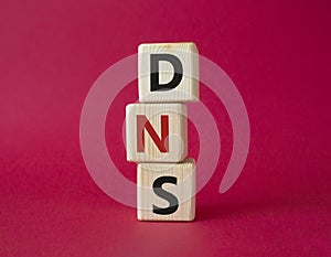 DNS - Domain Name Server - Consumer Price Index symbol. Concept word DNS on wooden cubes. Beautiful red background. Business and