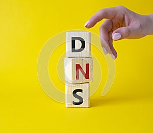 DNS -Domain Name Server - Consumer Price Index symbol. Concept word DNS on wooden cubes. Businessman hand. Beautiful yellow