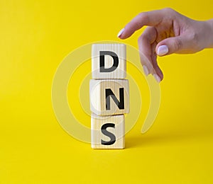 DNS -Domain Name Server - Consumer Price Index symbol. Concept word DNS on wooden cubes. Businessman hand. Beautiful yellow