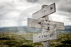 do amazing things text engraved on old wooden signpost outdoors in nature