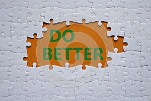 Do better symbol. White puzzle with words Do better. Beautiful orange background. Business and Do better concept. Copy space
