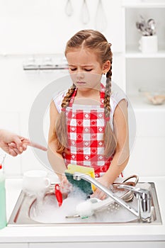 Do the dishes this instant - child ordered to wash up tableware photo