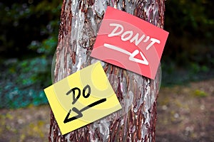 Do and don`t words written on papers on a tree with arrow signs. Dilemma between what to to or not to do