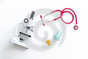 Do medical research with microscope, stethoscope, test-tubes in lab on white background top view