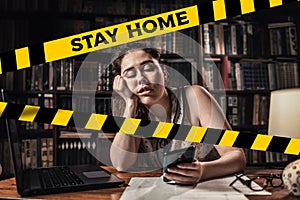 Do not cross.Barrier tape-quarantine,isolation.A young sleepy woman uses a mobile phone while working.The concept of quarantine