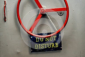 DO NOT DISTURB warning sign plate hanging on a hermetic bomb shelter armored door