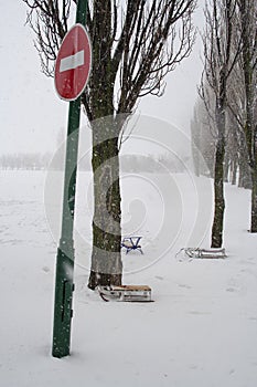 Do not enter traffic sign near the trees. Winter landscape. Baby sled near the trees