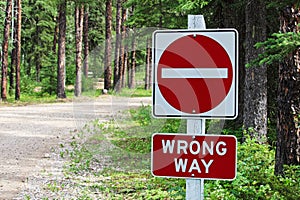 A do not enter, wrong way sign beside a gravel road