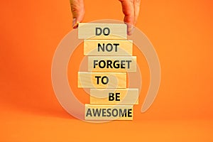 Do not forget to be awesome symbol. Concept words `Do not forget to be awesome` on wooden blocks on a beautiful orange backgroun