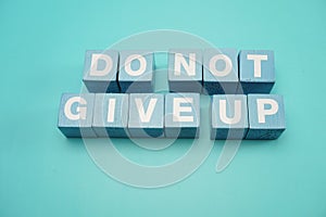 Do Not Give Up word made from wooden cube with letters alphabet on blue background