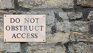 Do Not Obstruct Access sign on stone wall -  background banner image