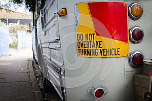 Do not overtake turning vehicle sign attached to the rear of the old vintage bus.