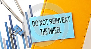 Do not reinvent the wheel text on sticker on the yellow notebook with chart and pen