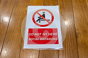Do not sitting and social distancing sign on the wooden bench