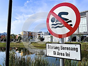 Do not swim sign near a lake in Indonesian language.