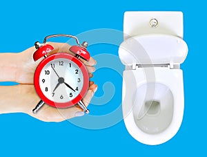 Do not waste your time advice.  Female hands with alarm clock is in the toilet. Wasting time concept. Isolated on blue, copy space