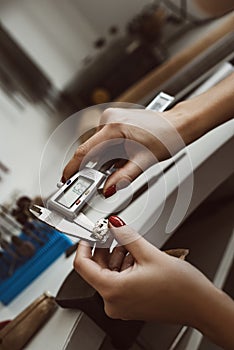 Do it right. Close up photo of female jeweler`s hands measuring ring with a tool in workshop.