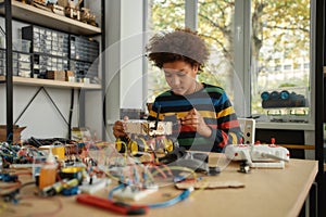 Do the right thing. Boy using screwdriver while fixing bolts on a robot vehicle. Smart kids and STEM education.