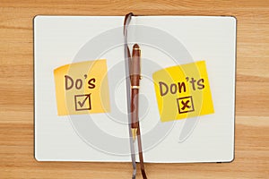 Do`s and Don`ts on two sticky notes in a journal with a pen