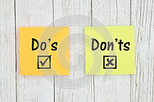 Do`s and Don`ts on two sticky notes  on weathered whitewash textured wood photo